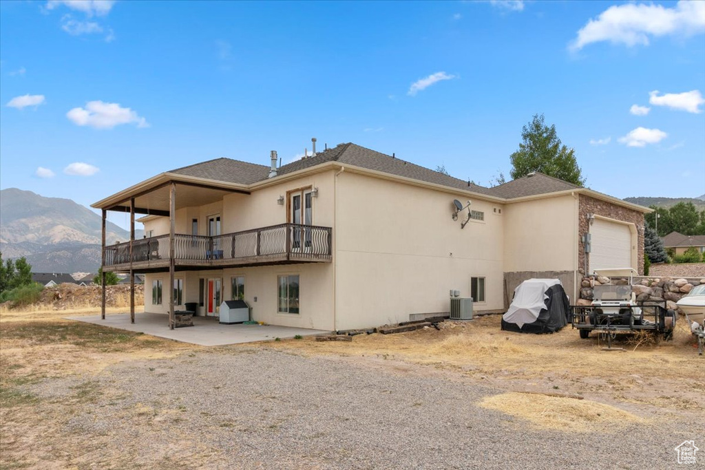 Rear view of property featuring a mountain view, a garage, stucco siding, and a patio