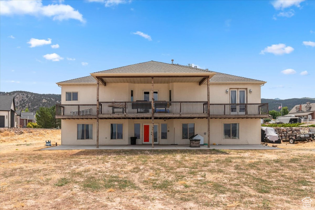Back of house featuring a patio area, stucco siding, a mountain view, french doors, and a balcony