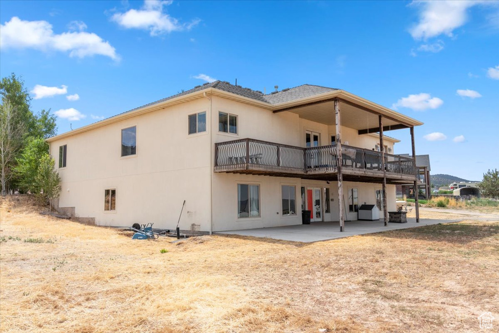 Back of property featuring a patio area, stucco siding, and a wooden deck