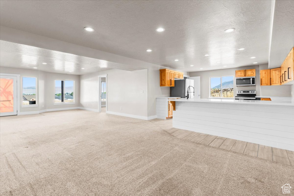 Unfurnished living room featuring light carpet, recessed lighting, a textured ceiling, and plenty of natural light