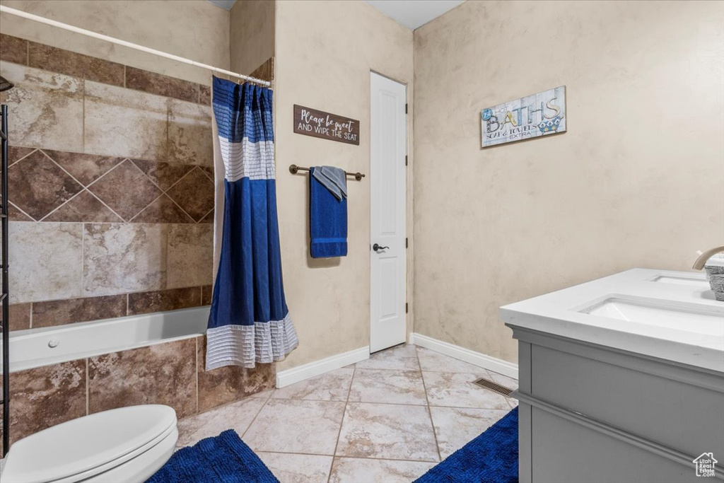 Bathroom featuring vanity, tiled shower / bath combo, and tile patterned flooring