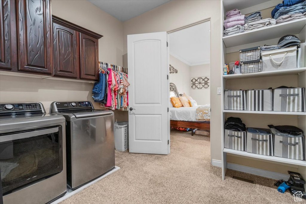 Washroom featuring separate washer and dryer, light colored carpet, and cabinet space