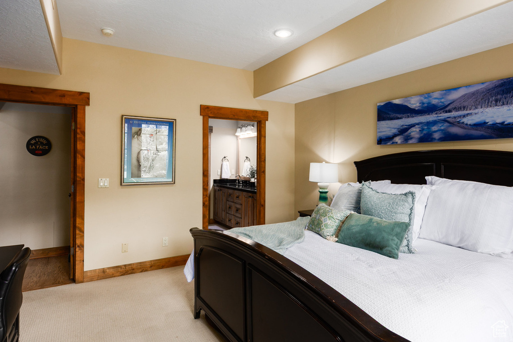 Bedroom featuring light colored carpet and ensuite bath