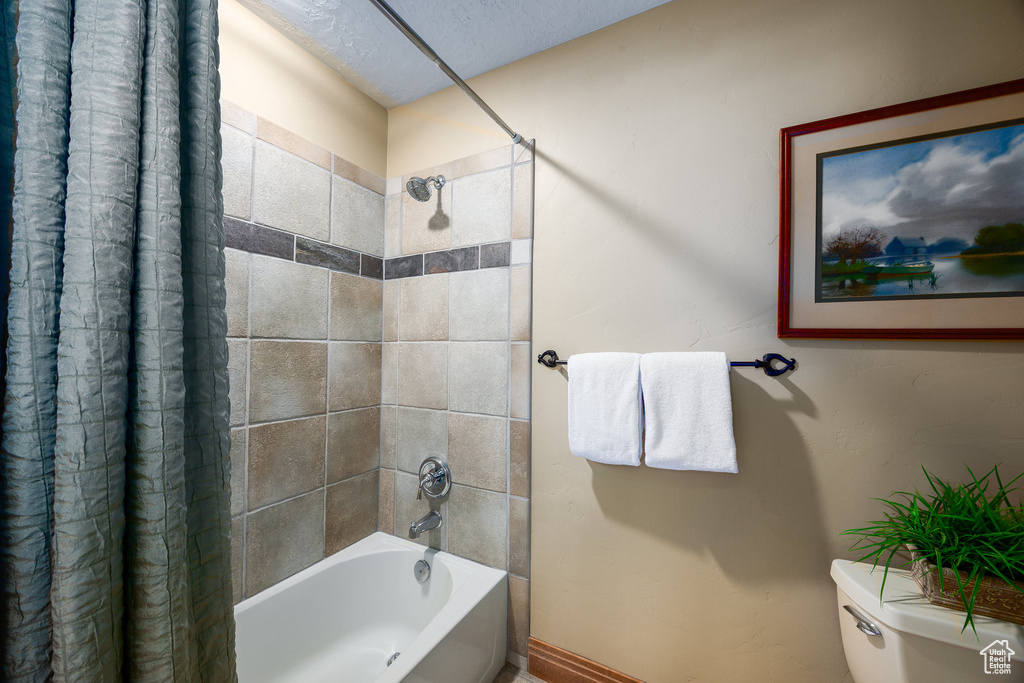 Bathroom featuring shower / bath combo with shower curtain and a textured ceiling