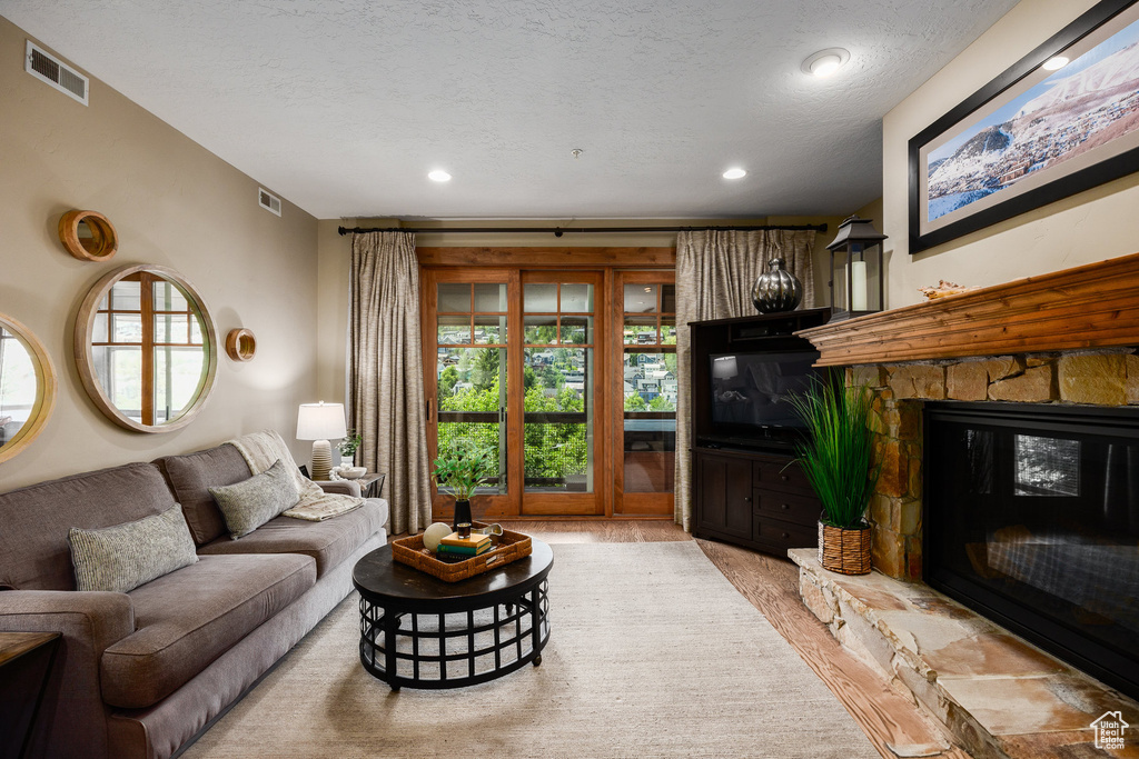 Living room featuring a fireplace, wood finished floors, a textured ceiling, and recessed lighting