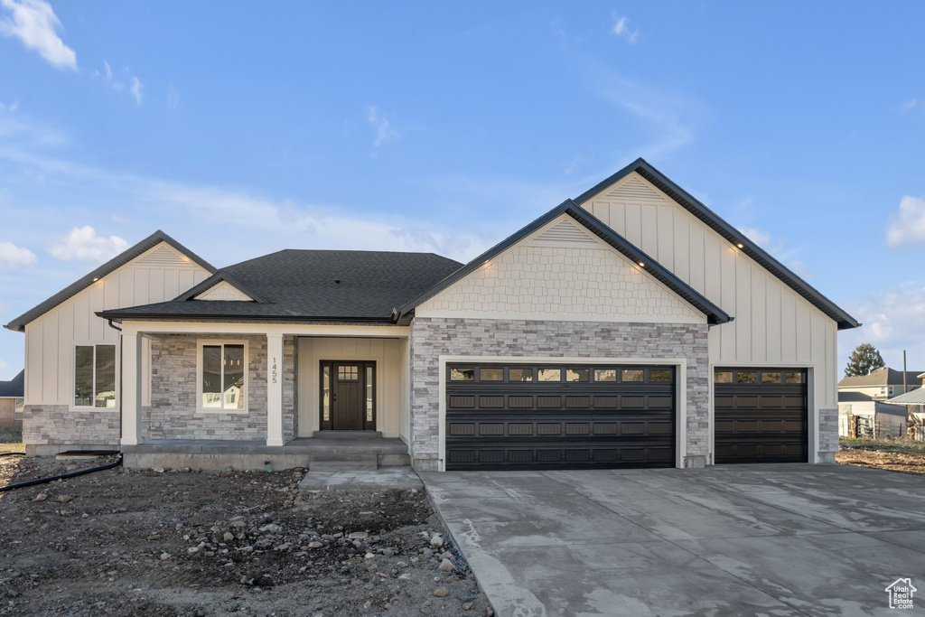 Modern inspired farmhouse featuring board and batten siding, an attached garage, driveway, and a porch