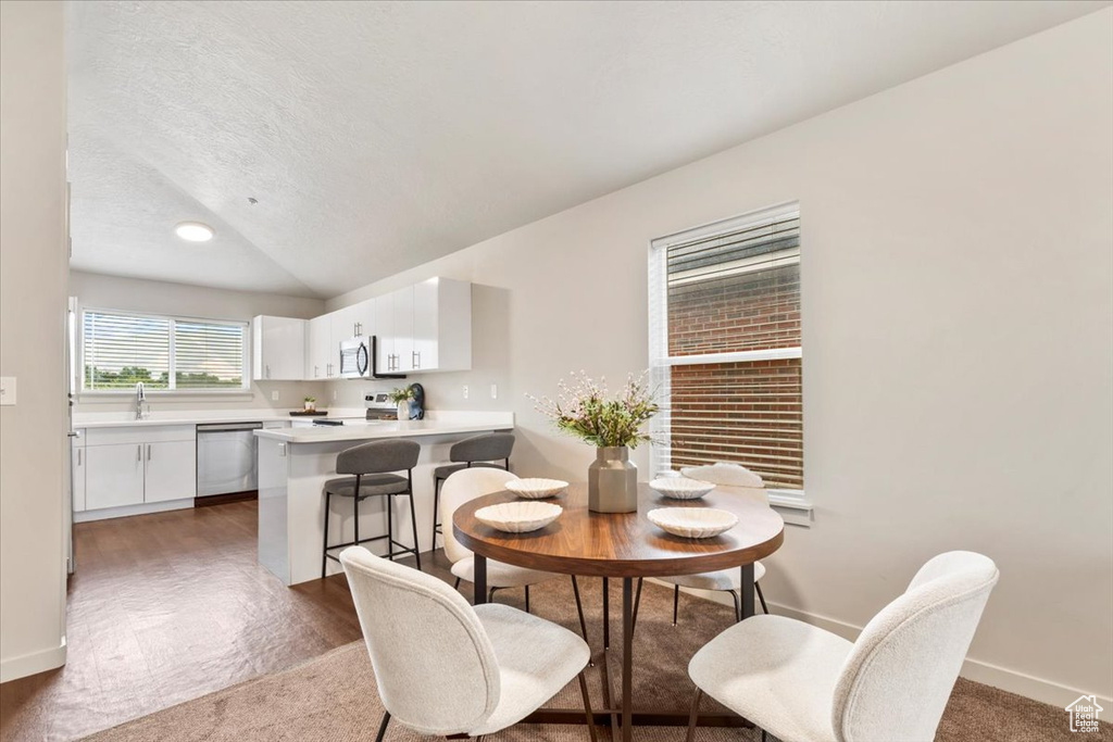 Carpeted dining space with a textured ceiling and vaulted ceiling