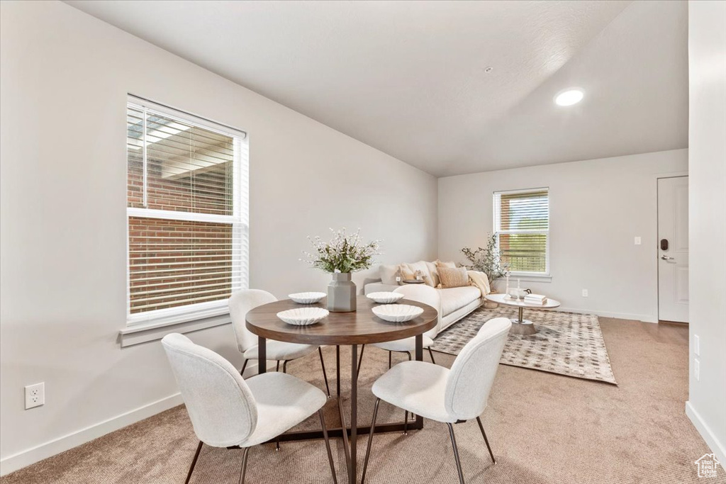 Carpeted dining space with baseboards and lofted ceiling