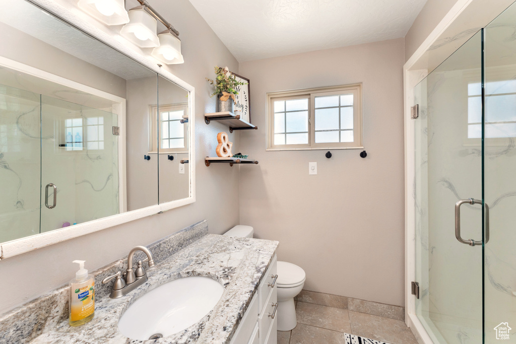 Bathroom with vanity, plenty of natural light, and a marble finish shower