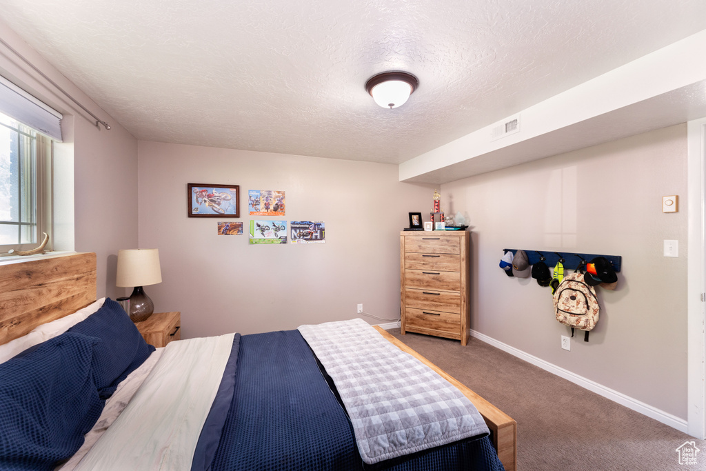 Bedroom with a textured ceiling and carpet flooring