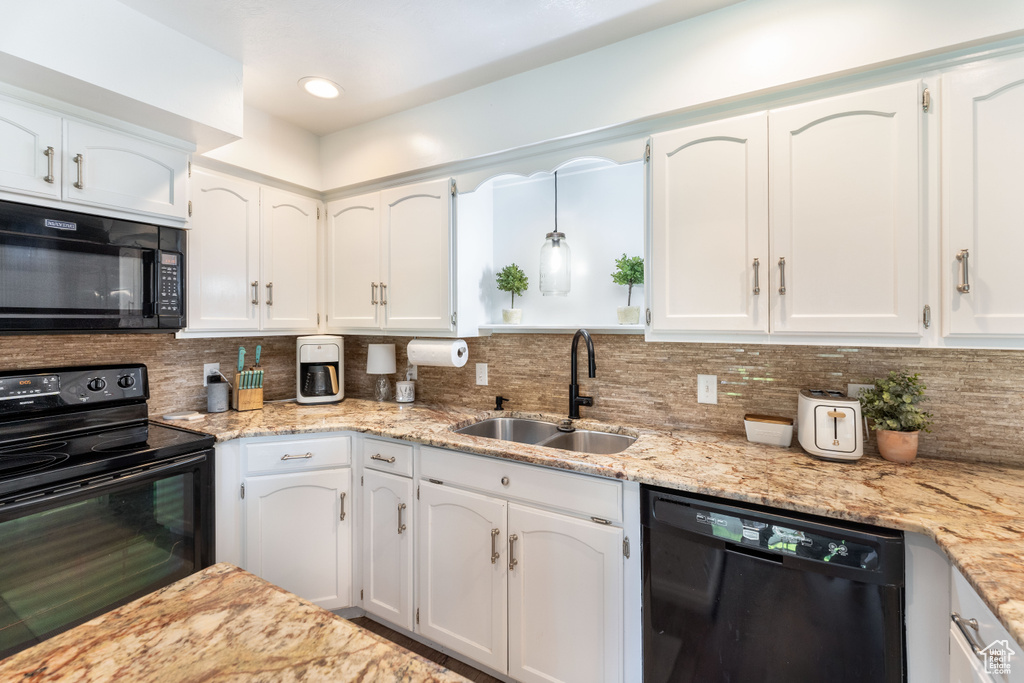 Kitchen featuring black appliances, white cabinetry, tasteful backsplash, and light stone countertops