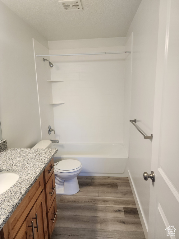 Full bathroom featuring vanity, wood finished floors, tub / shower combination, and a textured ceiling