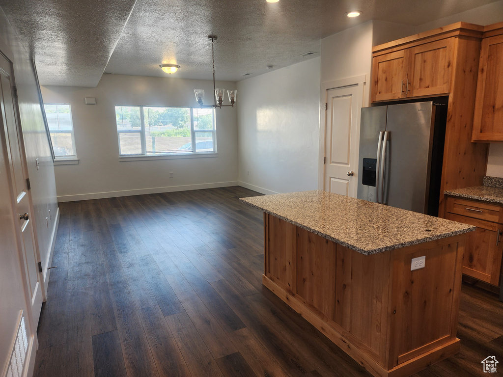 Kitchen with stainless steel fridge, a center island, brown cabinets, dark wood-style flooring, and a chandelier