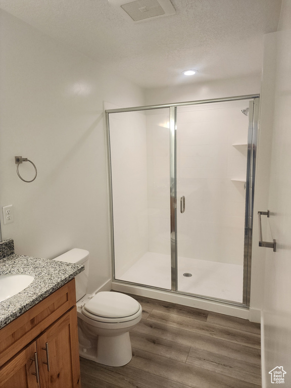 Bathroom featuring vanity, a shower stall, wood finished floors, and a textured ceiling