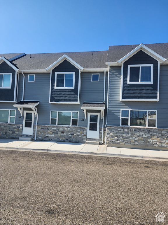 Craftsman house featuring entry steps, stone siding, and roof with shingles