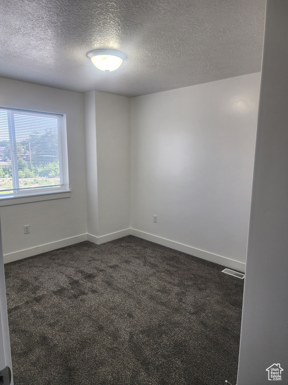Unfurnished room with dark colored carpet and a textured ceiling