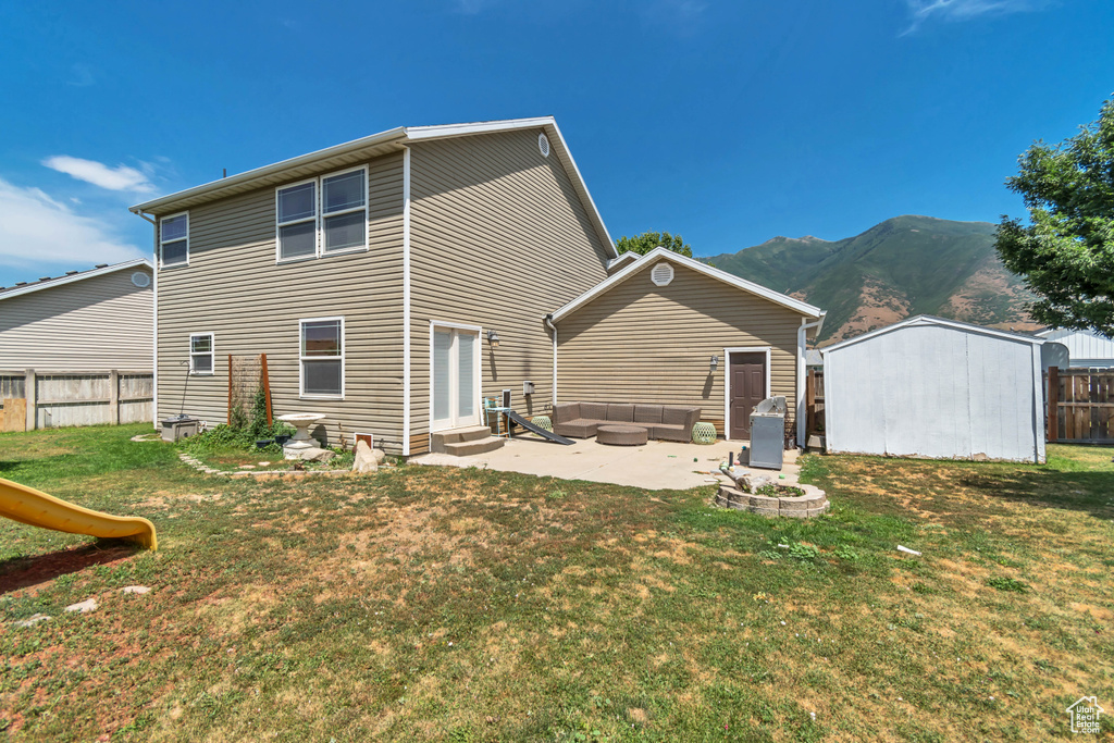 Rear view of property featuring outdoor lounge area, a patio, a mountain view, a fenced backyard, and a shed