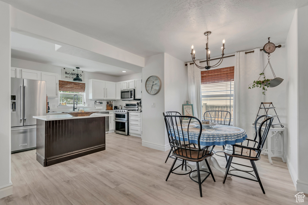 Kitchen featuring stainless steel appliances, a chandelier, light countertops, and light wood-type flooring