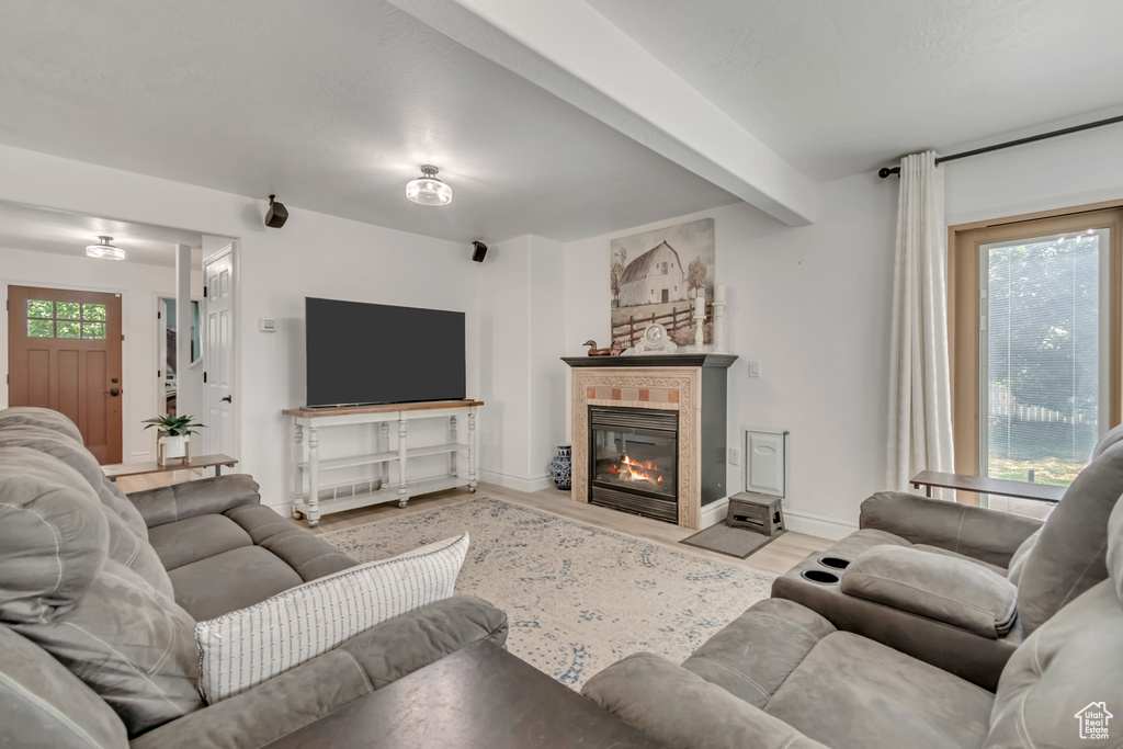 Living area featuring wood finished floors, a fireplace with flush hearth, and beam ceiling