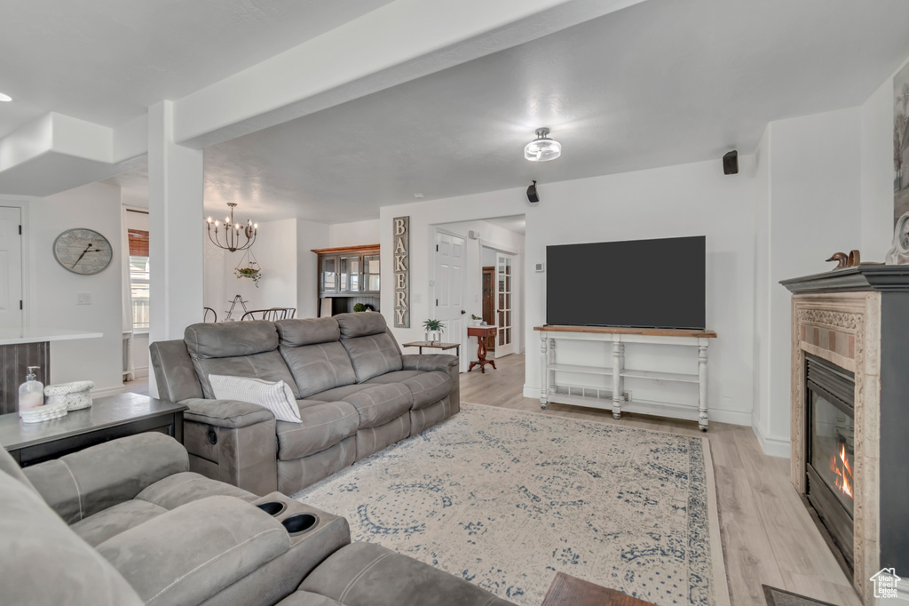 Living room with a chandelier, light wood-style floors, and a glass covered fireplace