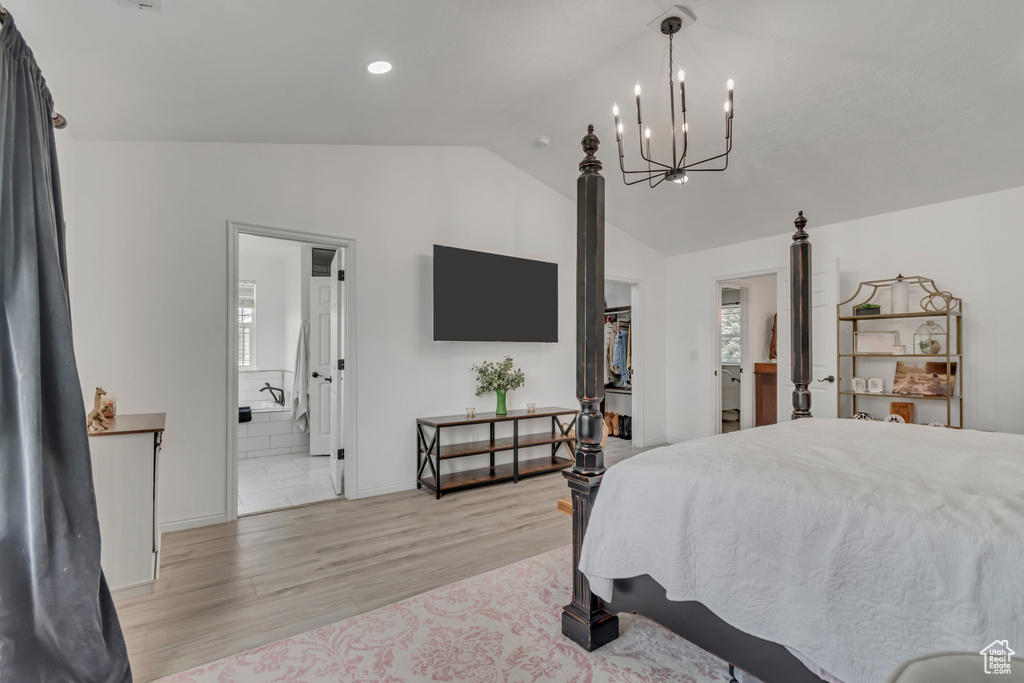 Bedroom with lofted ceiling, a chandelier, light wood-style floors, a walk in closet, and connected bathroom