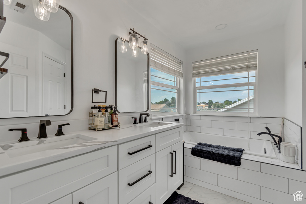 Full bath with double vanity, a bath, and marble finish floors