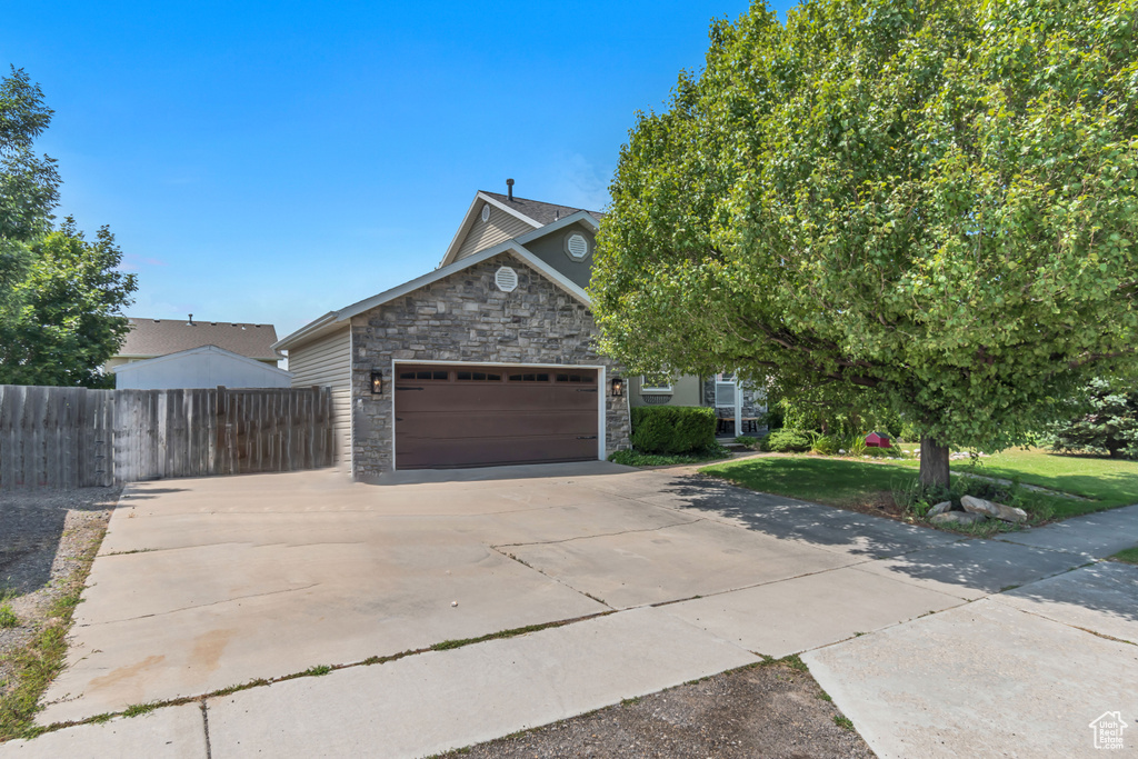 View of front of home featuring stone siding, a garage, and concrete driveway