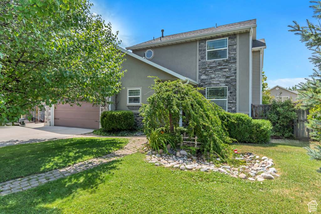 View of front of home featuring stone siding, stucco siding, driveway, and a garage