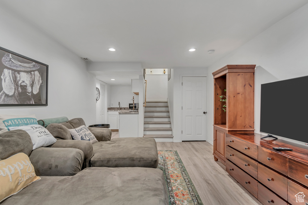 Living area with light wood finished floors, stairway, and recessed lighting