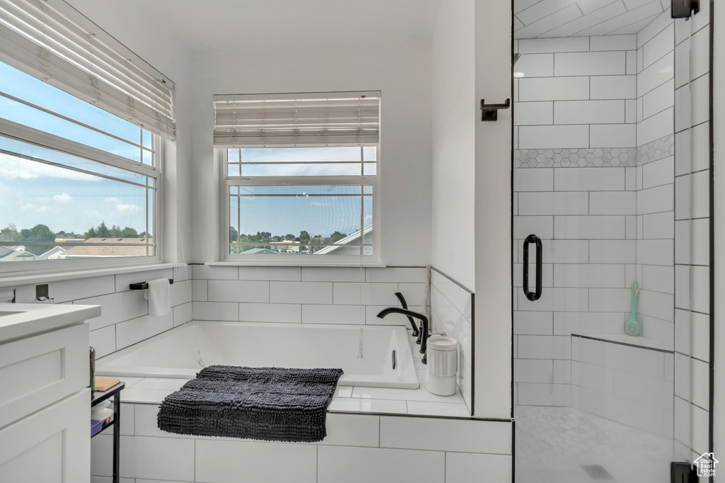 Bathroom featuring a shower stall, a bath, and vanity