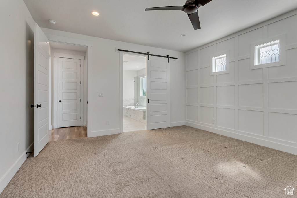 Unfurnished bedroom featuring carpet, a barn door, recessed lighting, and connected bathroom