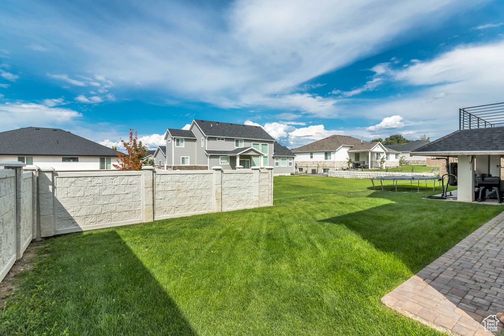 Fenced backyard featuring a trampoline, a residential view, and a patio