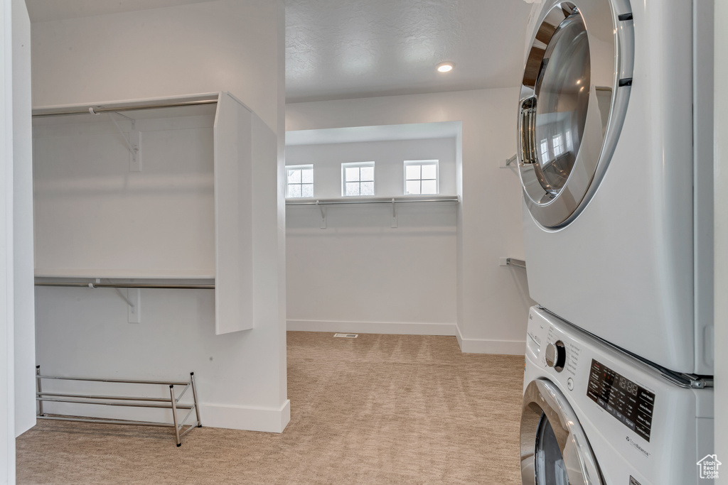Laundry room featuring stacked washer and clothes dryer and carpet floors
