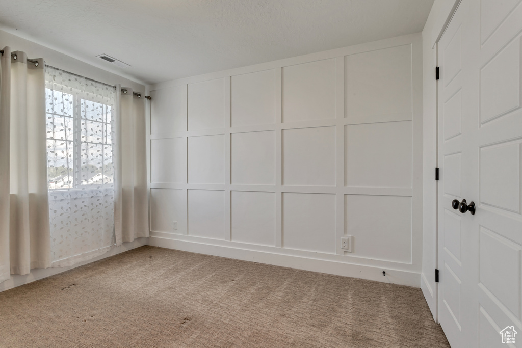 Unfurnished room featuring a decorative wall and carpet flooring