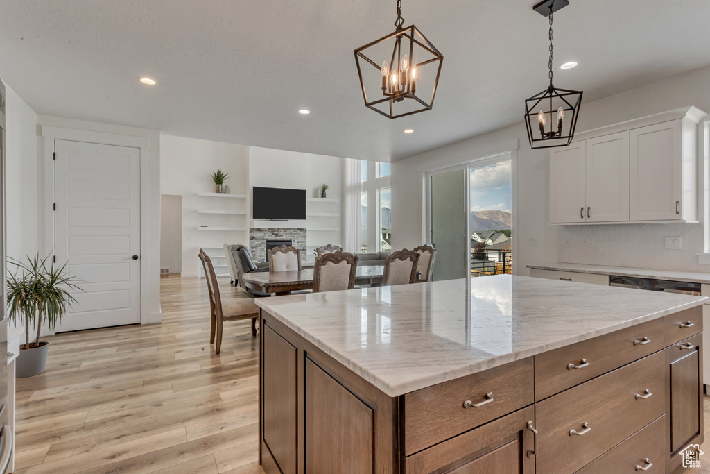 Kitchen featuring a chandelier, a fireplace, recessed lighting, white cabinetry, and light wood-style floors