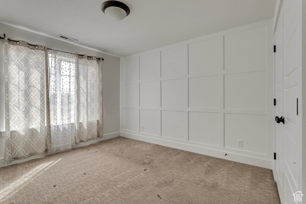 Carpeted spare room featuring a decorative wall
