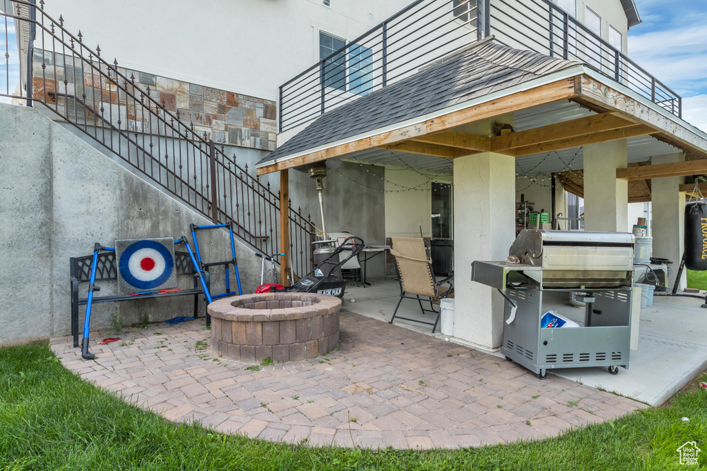 View of patio with an outdoor fire pit, stairs, and a grill
