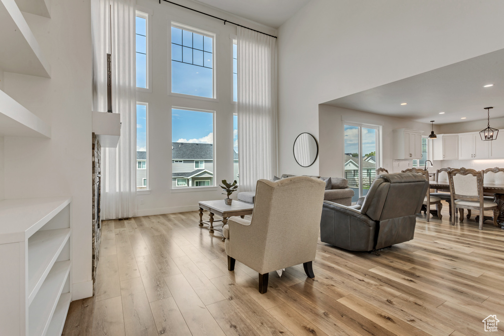 Living area with healthy amount of natural light, a towering ceiling, light wood-style flooring, and recessed lighting