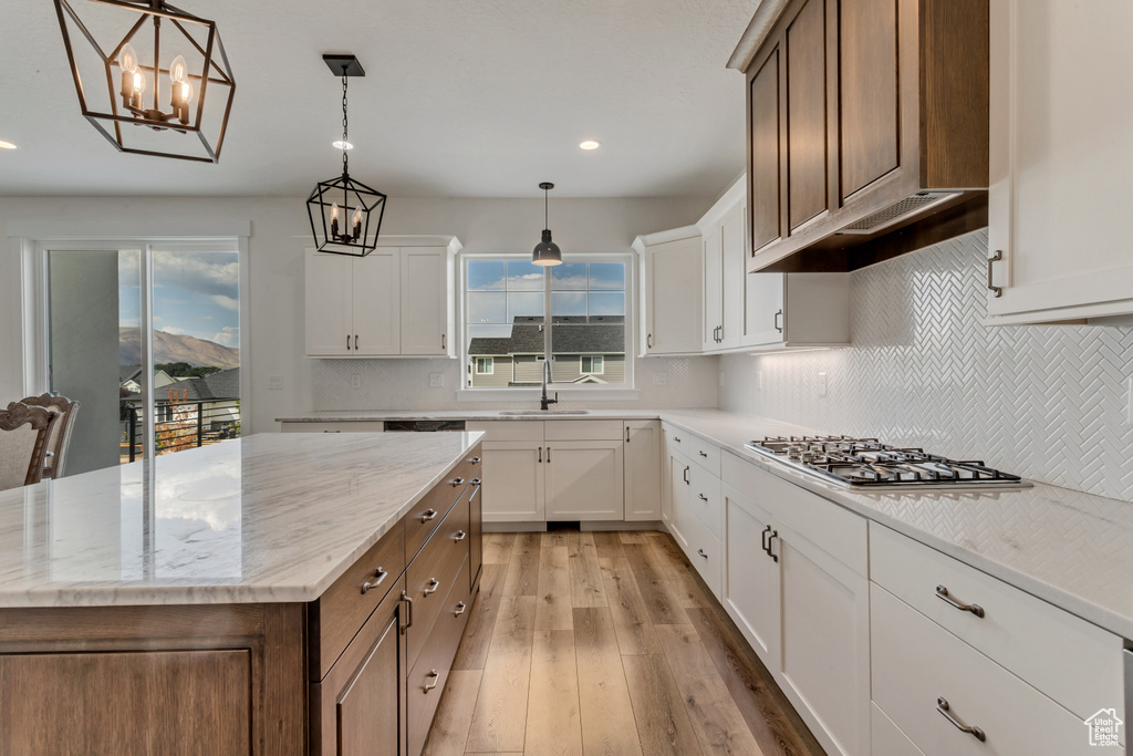 Kitchen with light wood-style flooring, recessed lighting, a chandelier, white cabinetry, and light stone counters