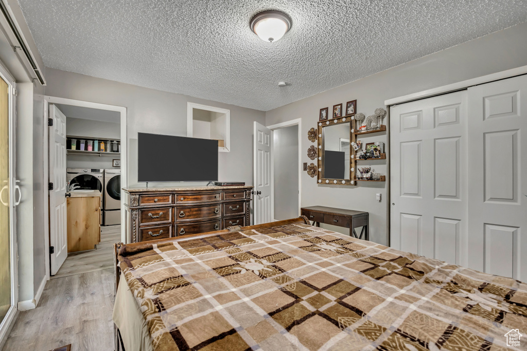 Bedroom featuring washer and dryer, a closet, light wood-style floors, and a textured ceiling