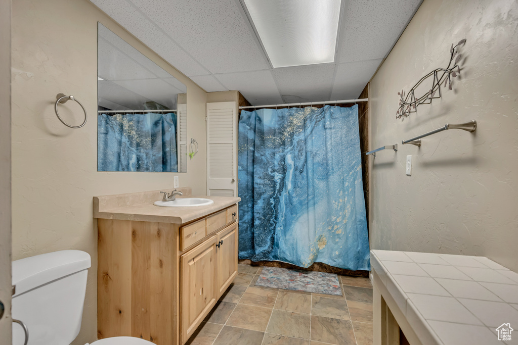 Full bathroom with vanity, stone finish flooring, a paneled ceiling, and a shower with curtain