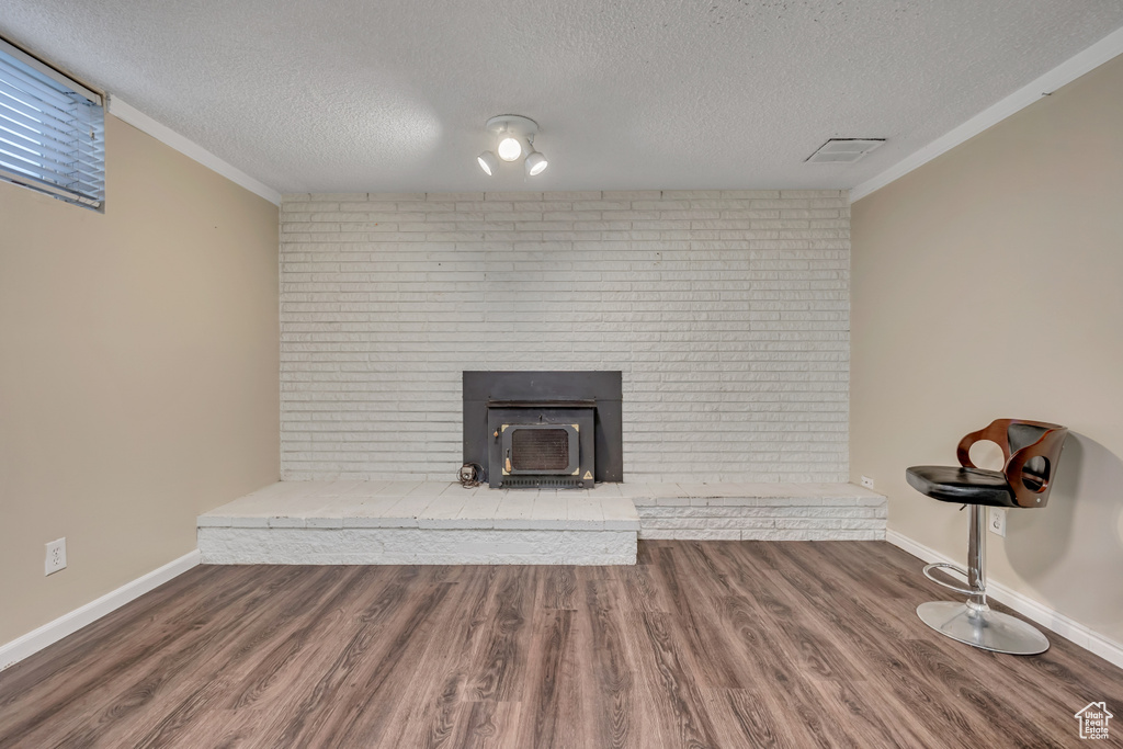 Detailed view of a textured ceiling, wood finished floors, and ornamental molding