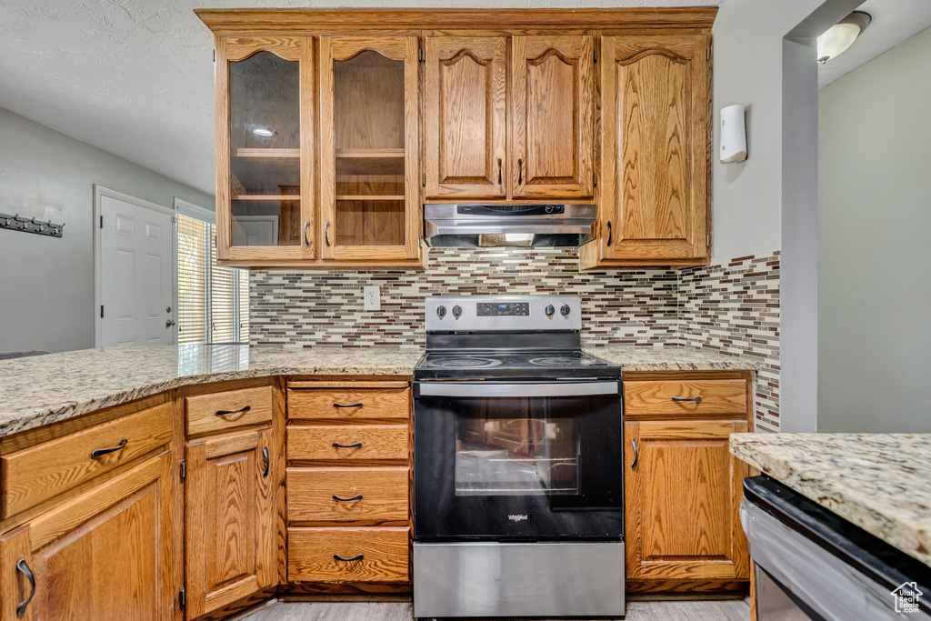 Kitchen with stainless steel range with electric stovetop, light wood-style flooring, and backsplash