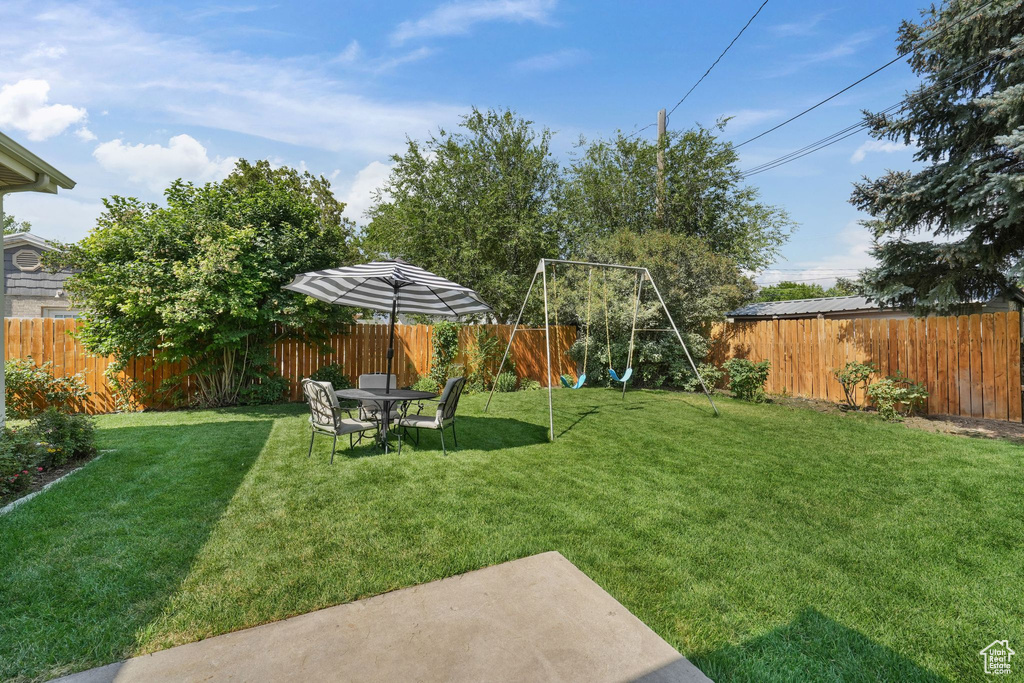 Fenced backyard featuring a playground and a patio