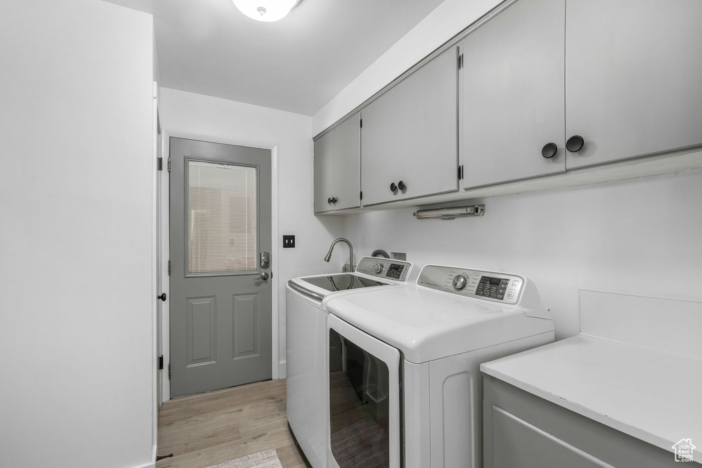 Laundry room featuring cabinet space, washer and dryer, and light wood finished floors