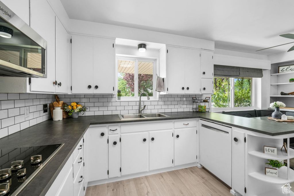 Kitchen featuring open shelves, dark countertops, stainless steel microwave, and black electric cooktop