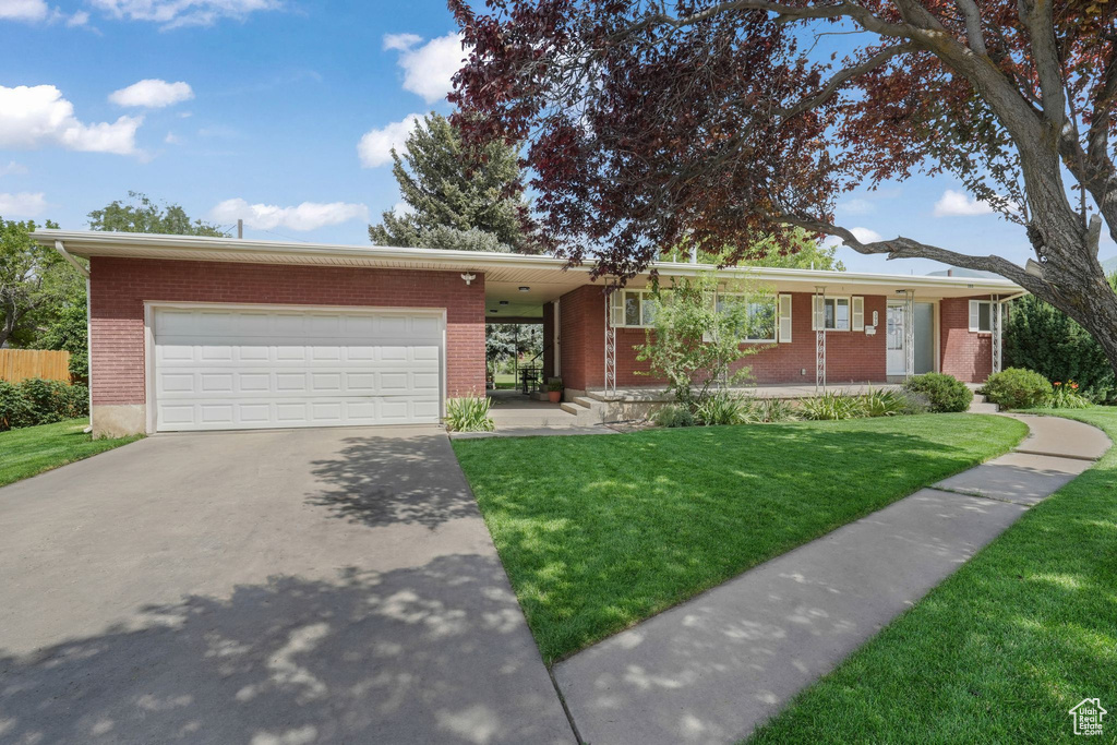 Single story home with a garage, a front lawn, driveway, brick siding, and a porch