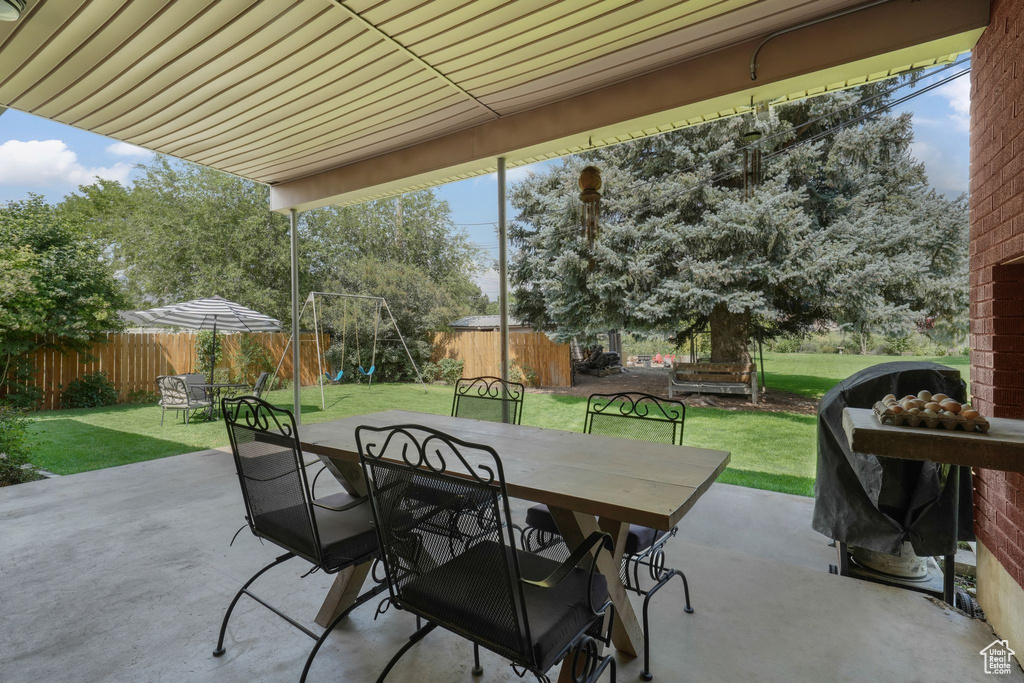 Fenced backyard with a patio area, outdoor dining area, a playground, and area for grilling