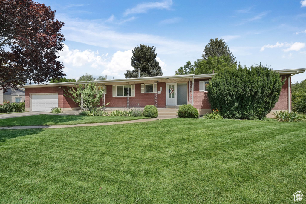 Ranch-style home featuring a garage, concrete driveway, brick siding, and a front lawn