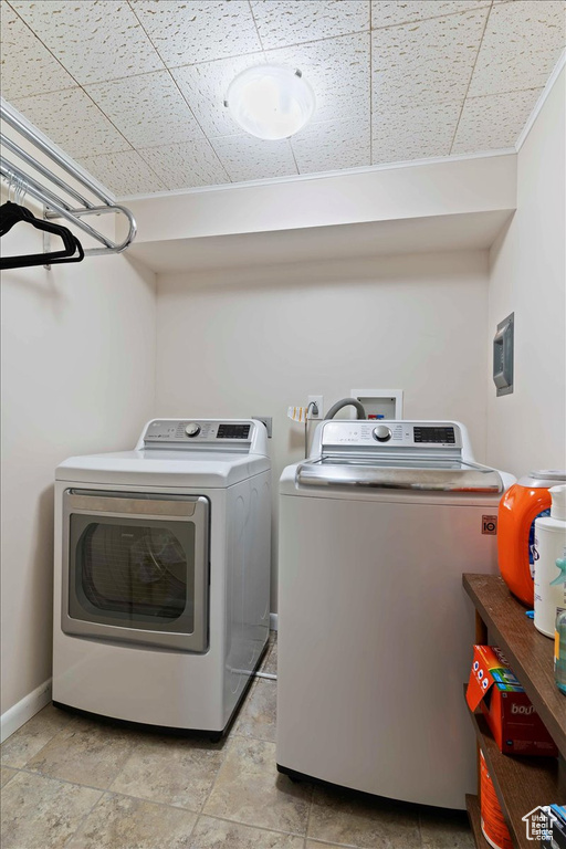 Laundry area featuring independent washer and dryer and light stone finish flooring